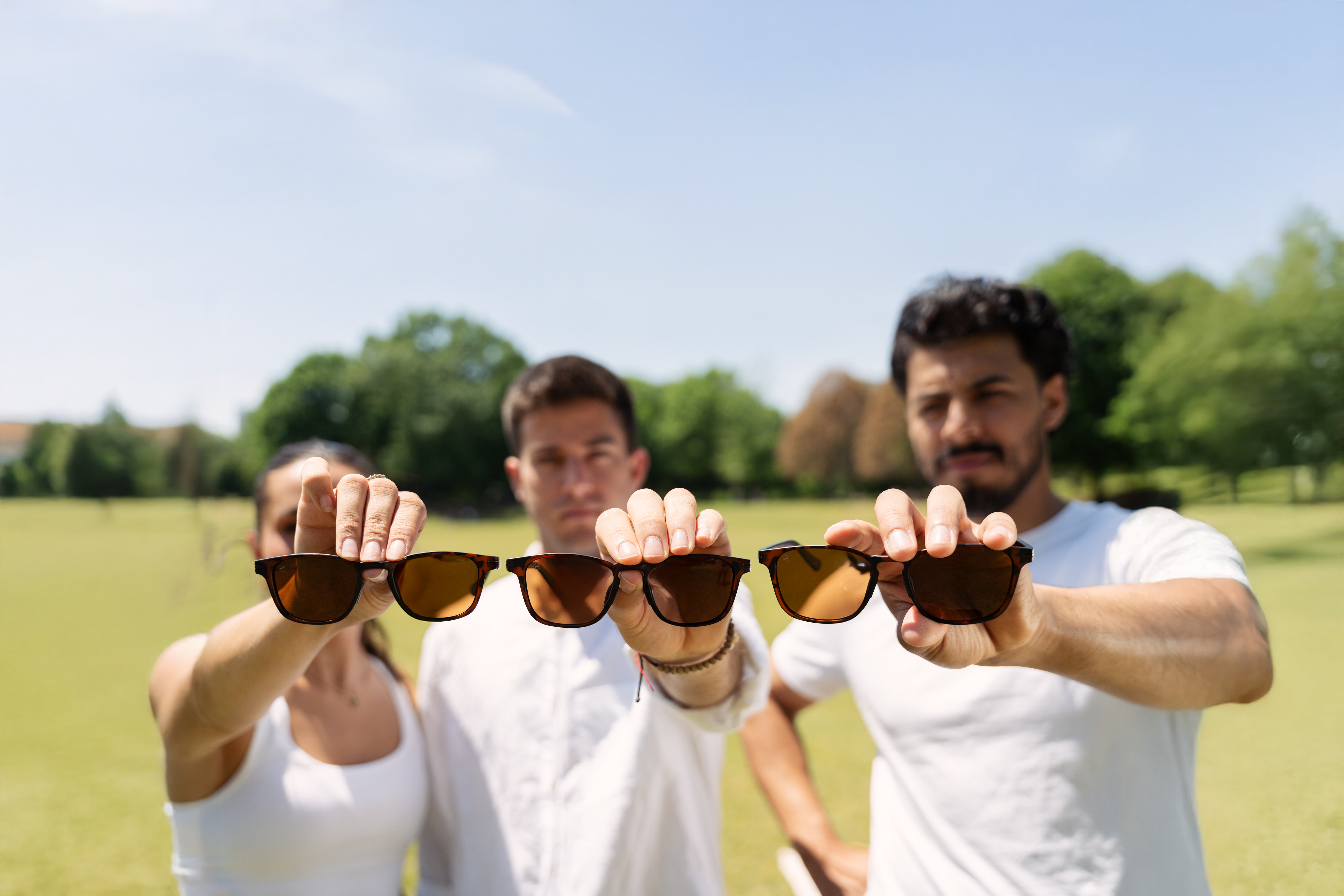 Three people holding up small, medium, and large sunglasses
